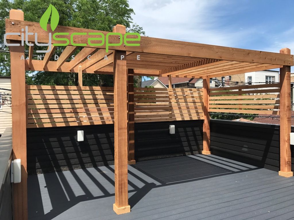 Wooden pergola with slatted walls on a deck, casting shadows.