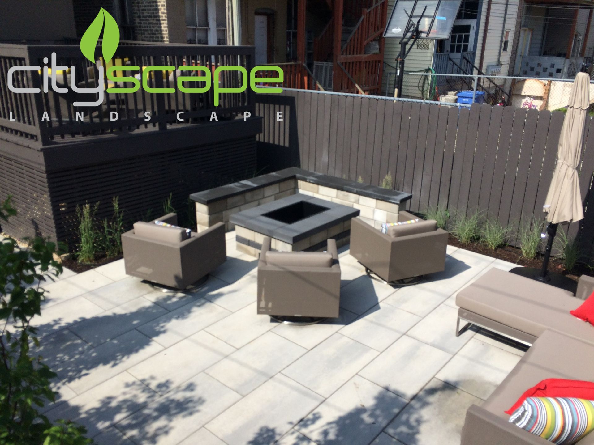 Patio with fire pit, seating, gray pavers, and brown fence.