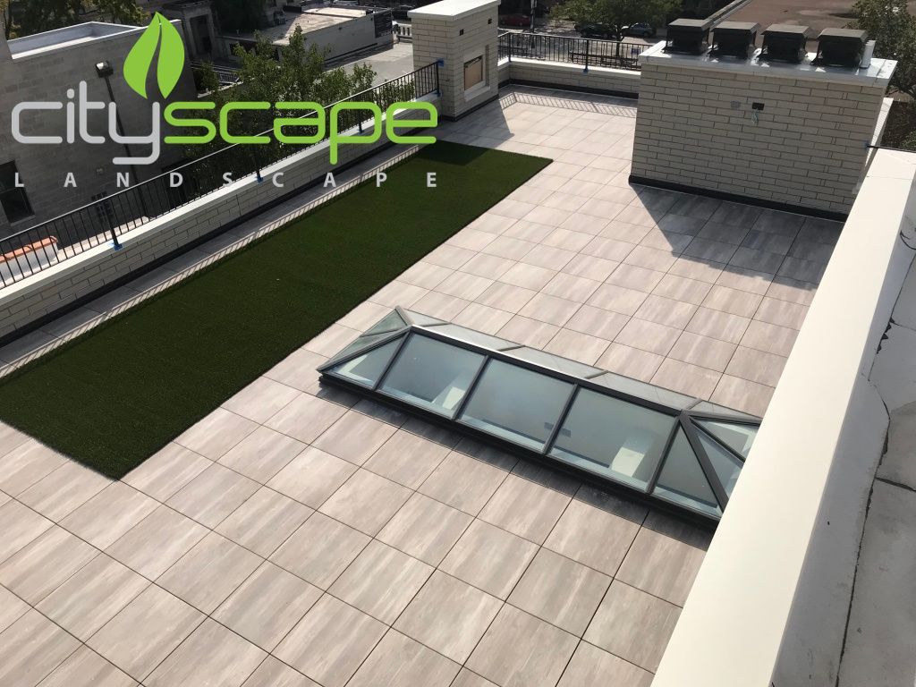 Rooftop patio with artificial turf, skylight, and light-colored pavers. Cityscape Landscape logo visible.