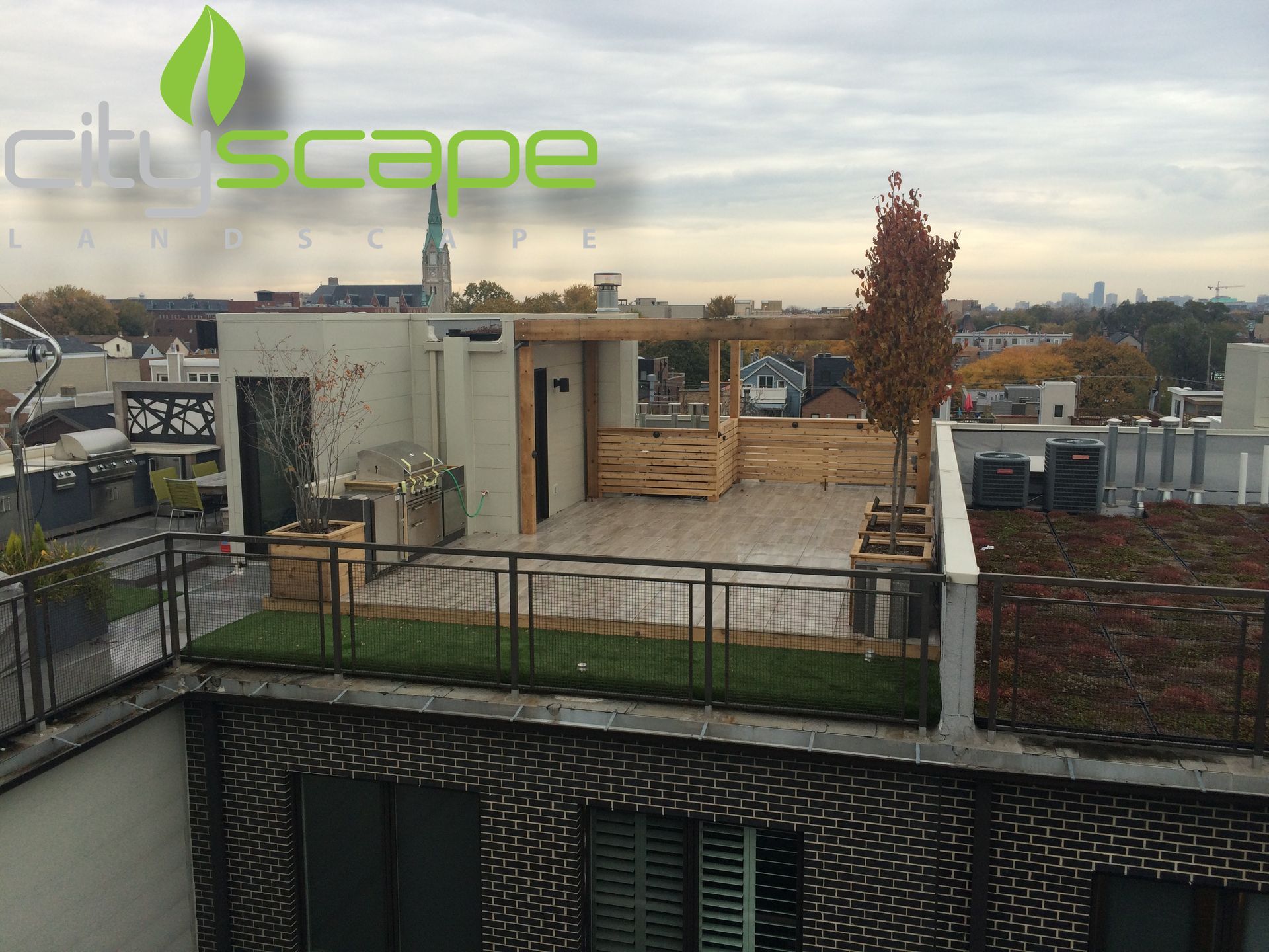 Rooftop garden with artificial turf, wooden structures, and city view under an overcast sky.