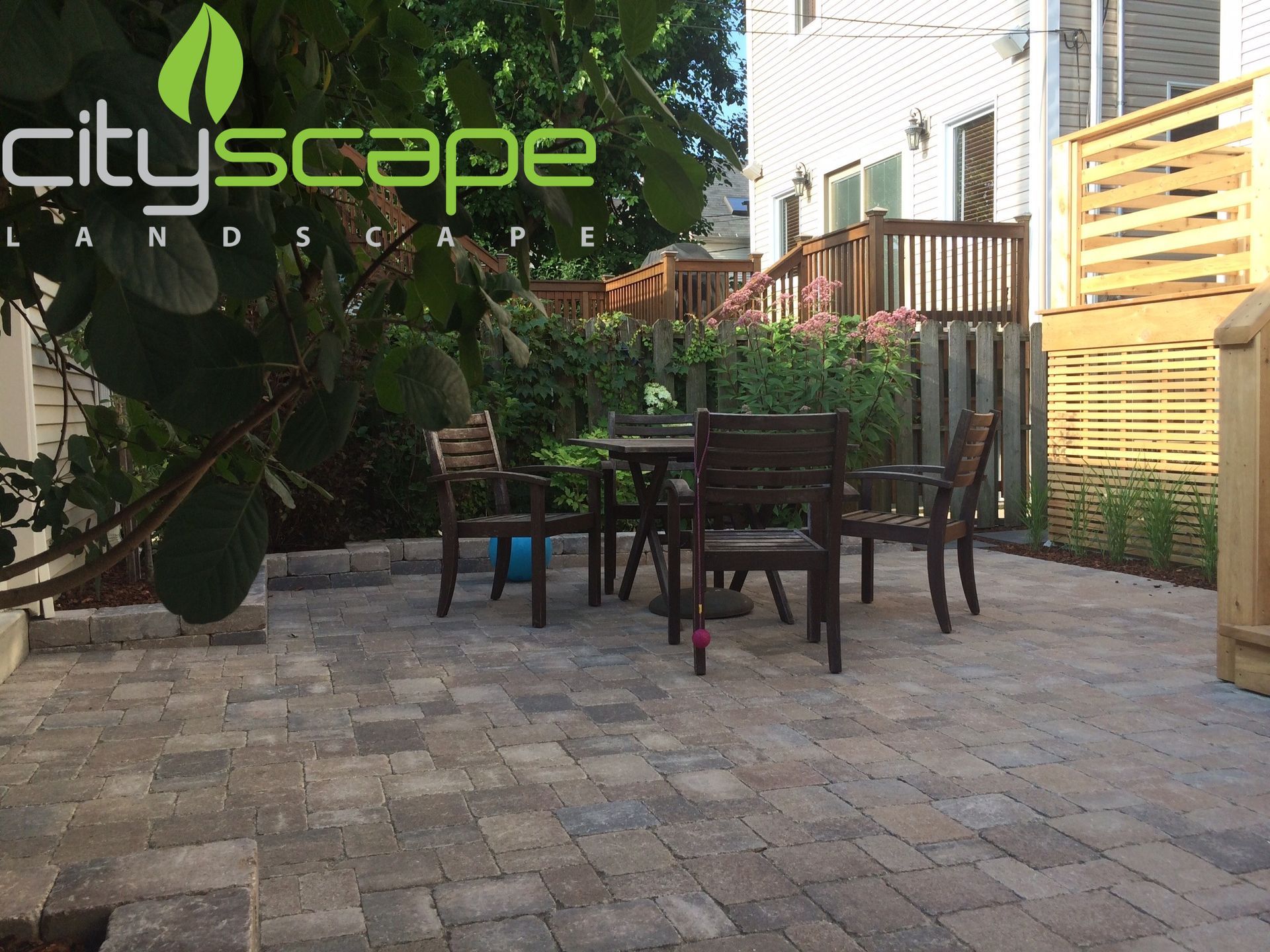 Patio with dining set, surrounded by landscaping, with a Cityscape Landscape logo.