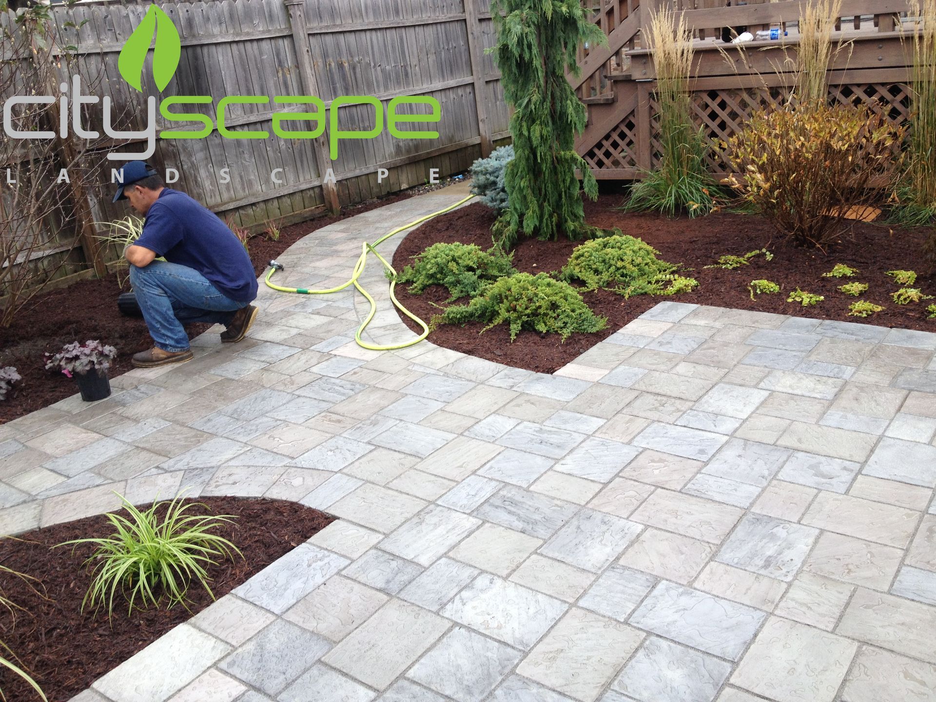 Man landscaping a stone patio and garden with mulch.