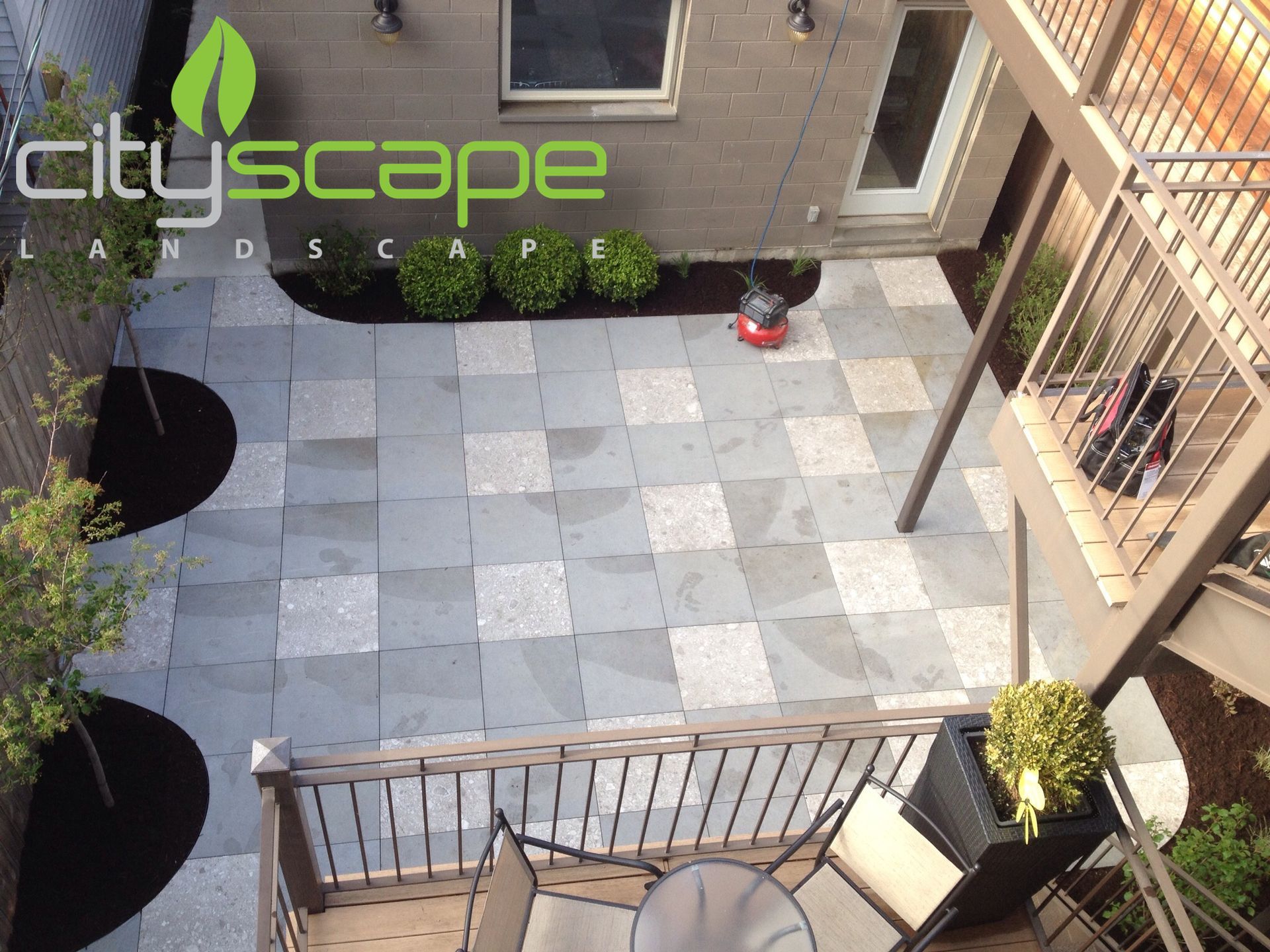 Overhead view of a modern patio with stone pavers, landscaping, and a multi-level deck.