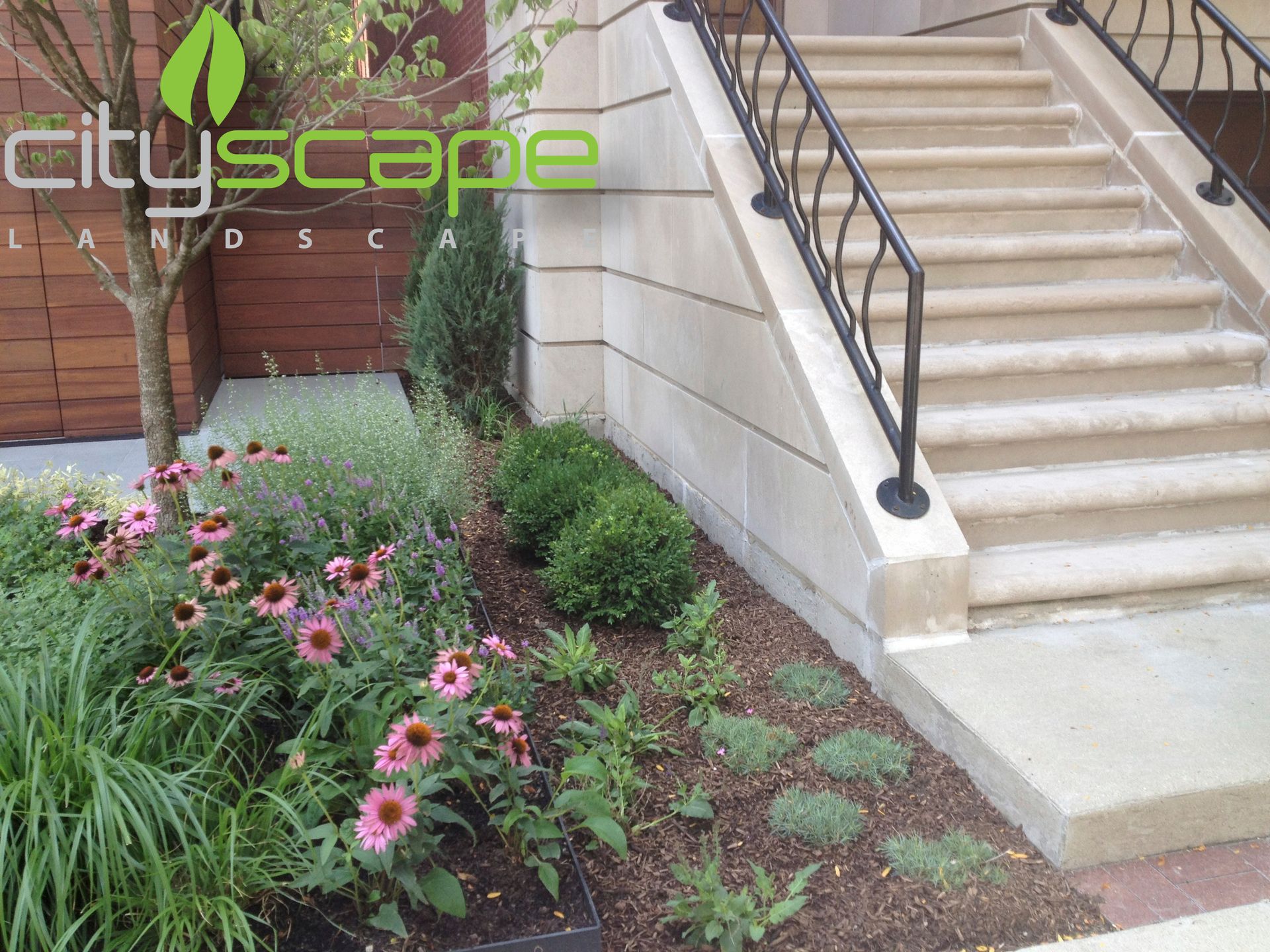 Landscaped garden bed with pink flowers and a stone staircase.