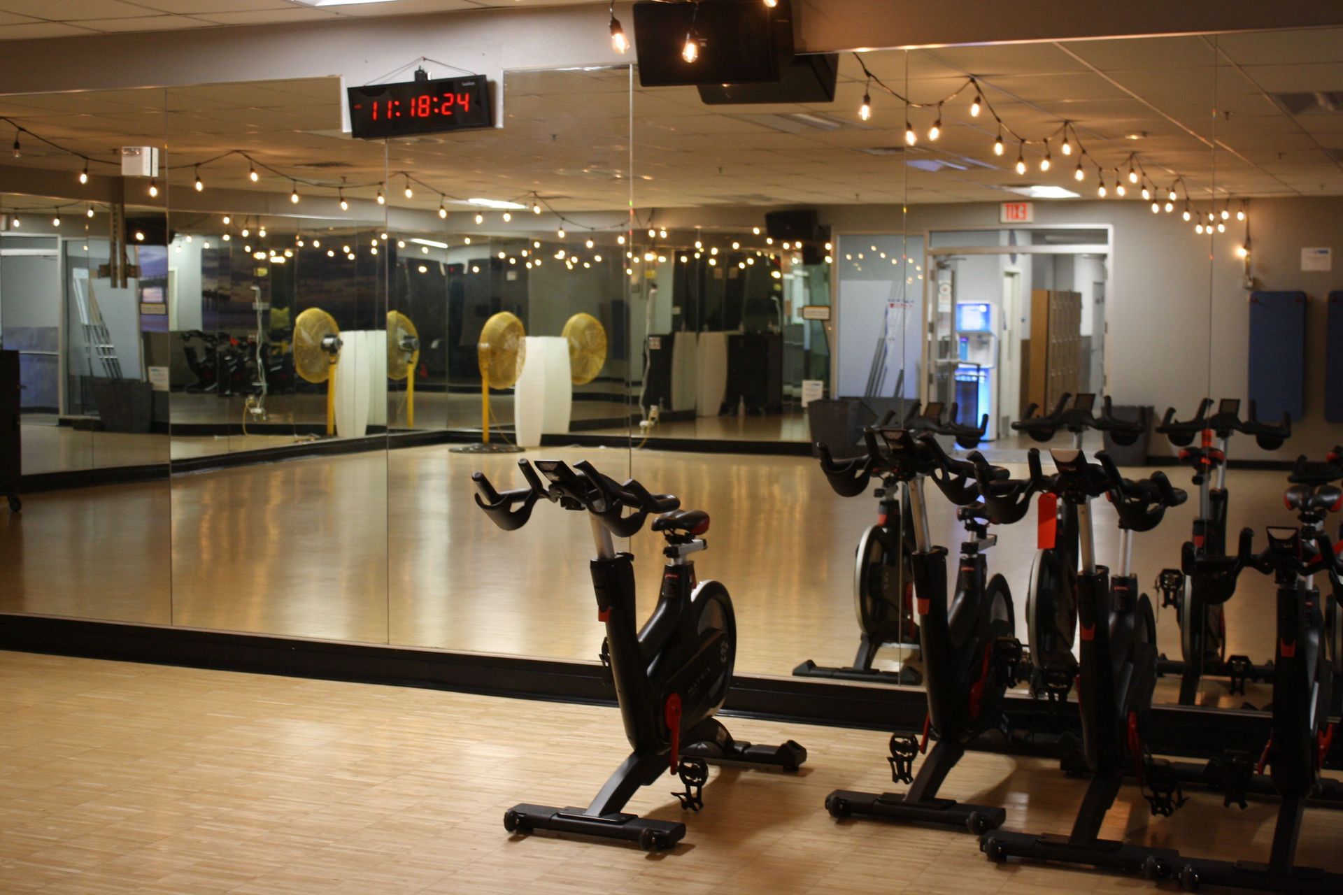 A row of exercise bikes are lined up in front of a large mirror in a gym