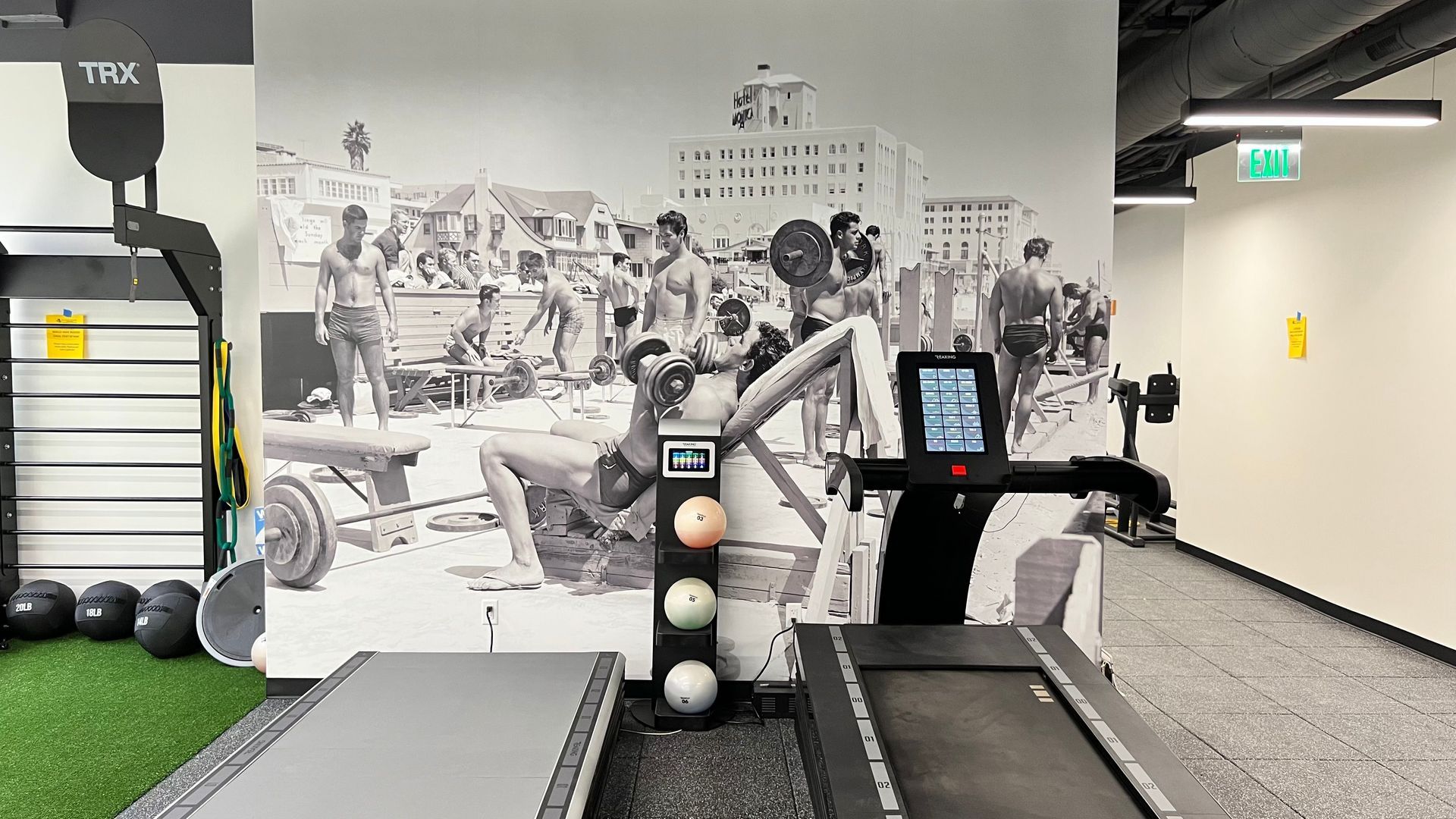 A treadmill in a gym with a picture on the wall behind it.