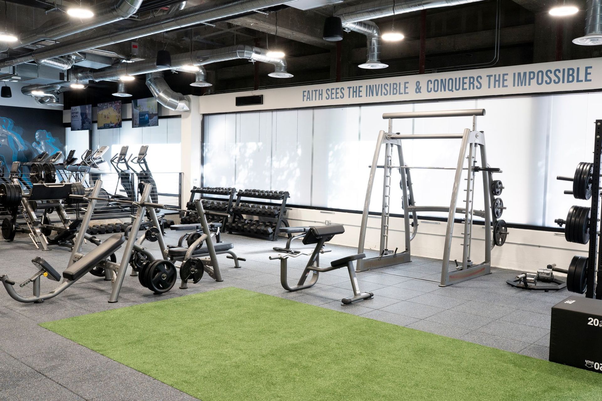 A gym filled with lots of exercise equipment and a sign that says `` conquers the impossible ''.