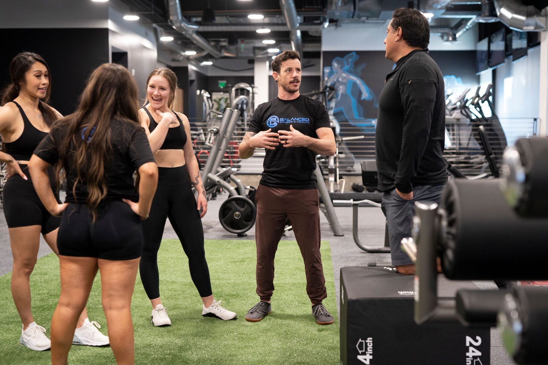 A group of people are standing in a gym talking to each other.