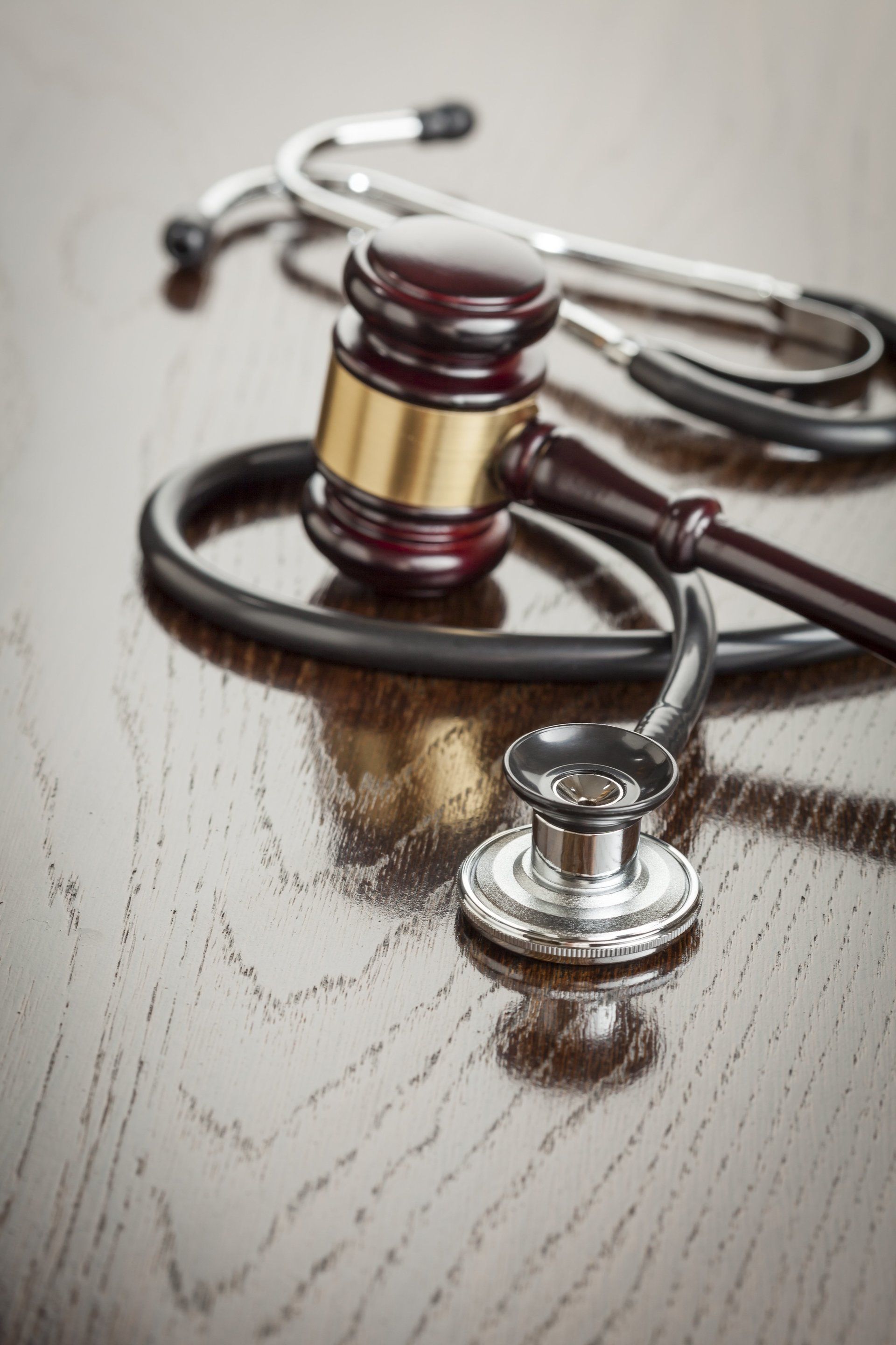 A judge 's gavel and stethoscope are on a wooden table.