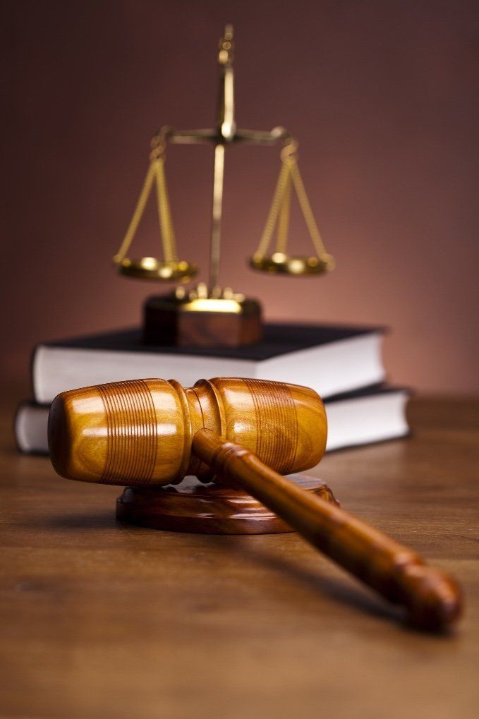 A wooden gavel and scales of justice are on a wooden table.