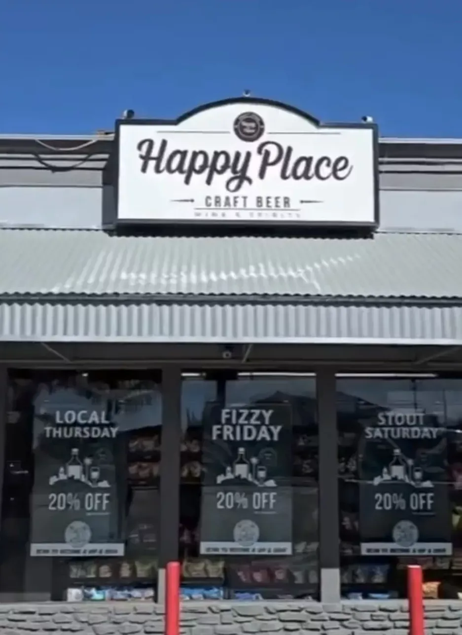 Happy Place Craft Beer storefront with signs in the windows advertising 20% off for Thursday, Friday, and Saturday.
