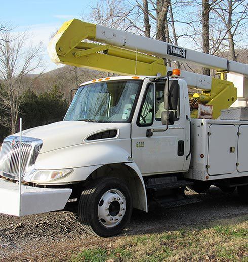 White utility truck with yellow boom, parked outdoors.