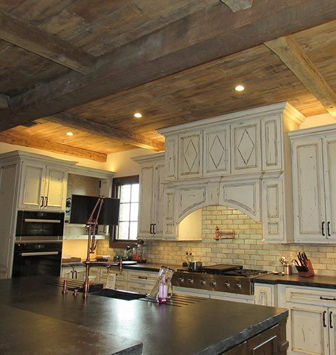Rustic kitchen with white cabinets, dark countertop, and exposed wood beams on the ceiling.