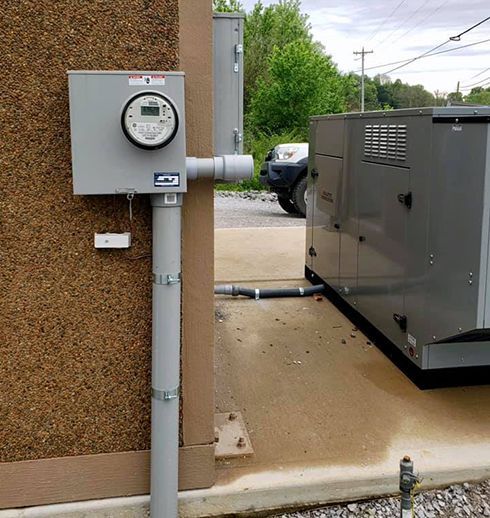 Electrical meter and conduit on a textured wall next to a generator outside.
