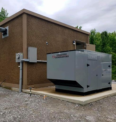 Generator outside a brown building with gray trim, on a concrete pad.