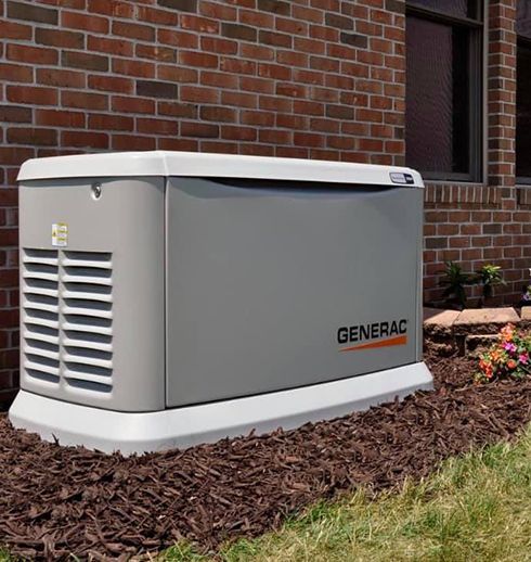Gray Generac home backup generator installed near a brick house.