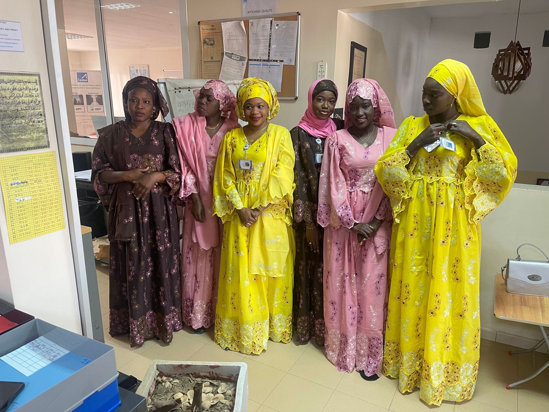 Un groupe de femmes en robes jaunes et roses se tiennent dans une pièce.