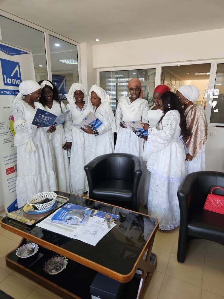 Un groupe de femmes en robes blanches se tiennent autour d'une table basse.