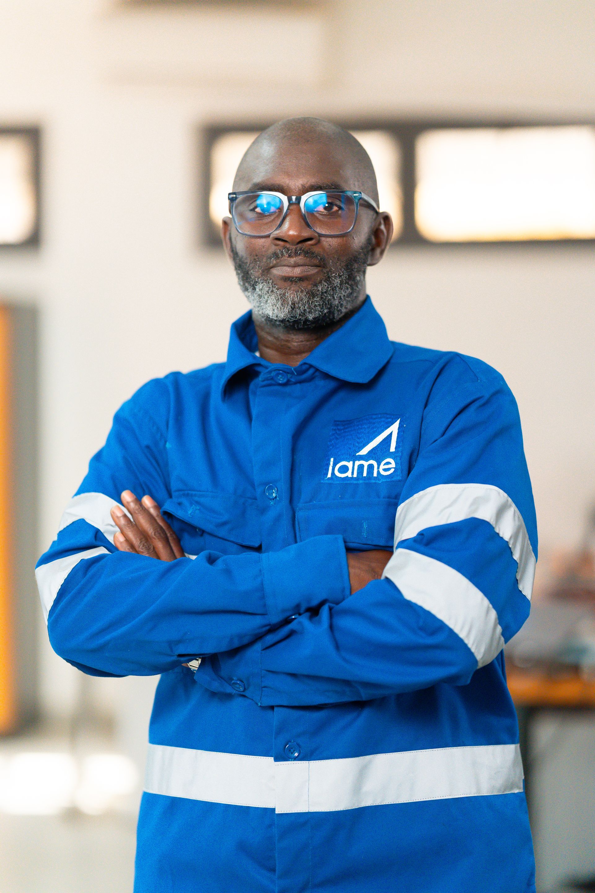 Un homme en combinaison bleue et blanche avec les bras croisés.