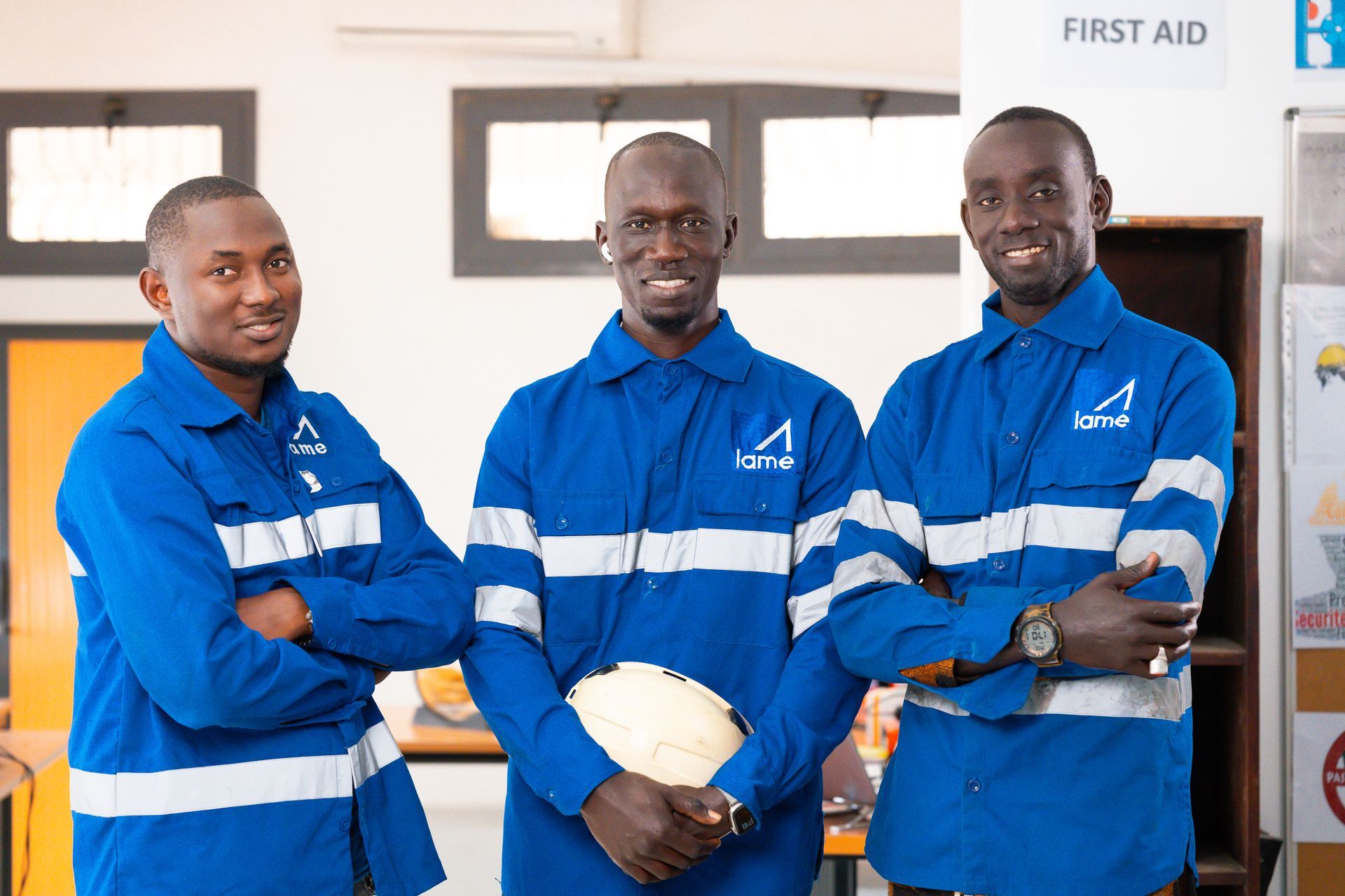 Trois hommes portant des gilets de sécurité bleus posent pour une photo.
