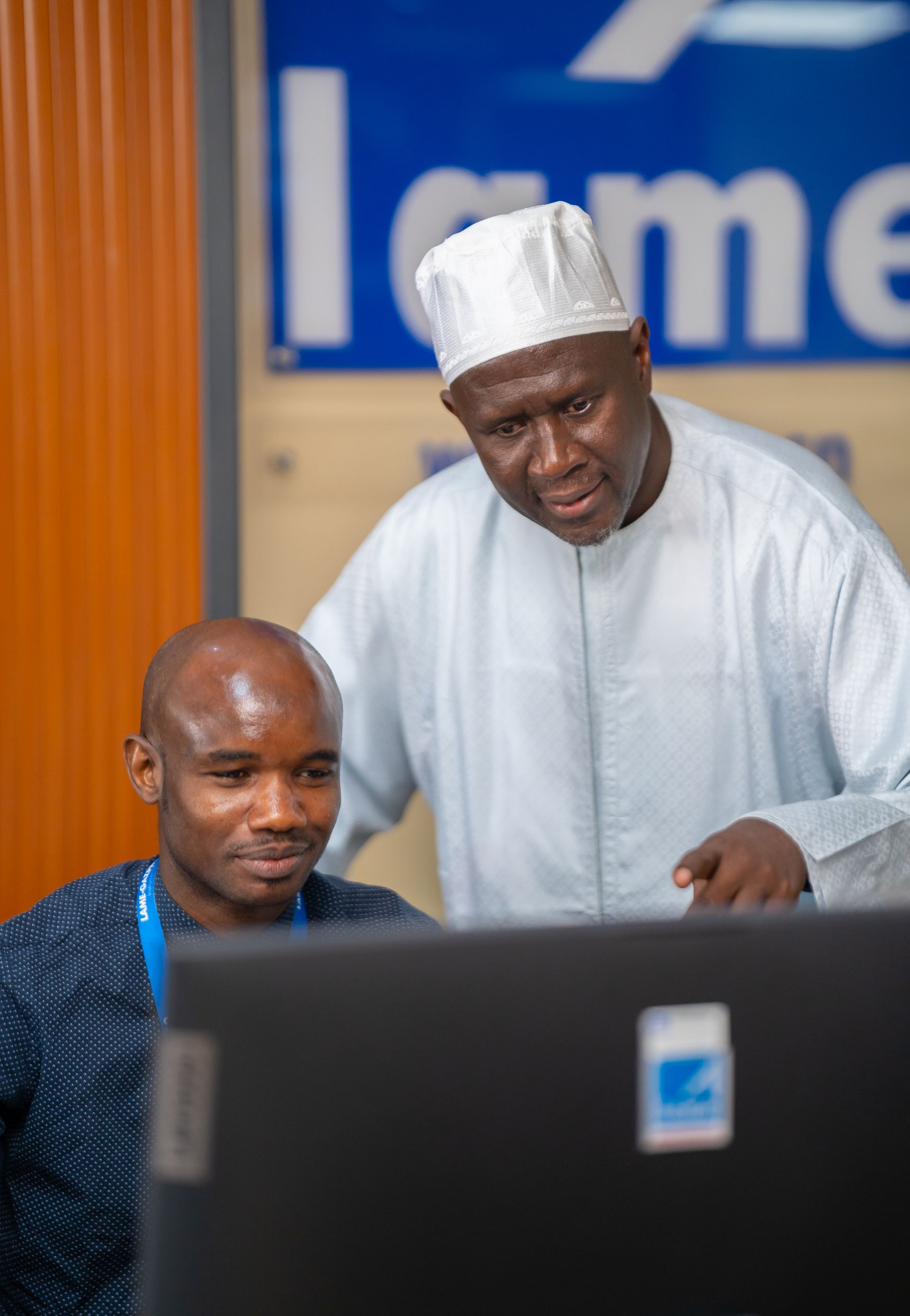 Deux hommes regardent ensemble un écran d'ordinateur.