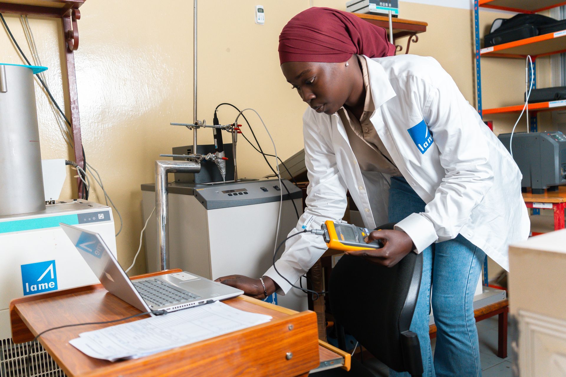 Une femme en blouse de laboratoire travaille sur un ordinateur portable.