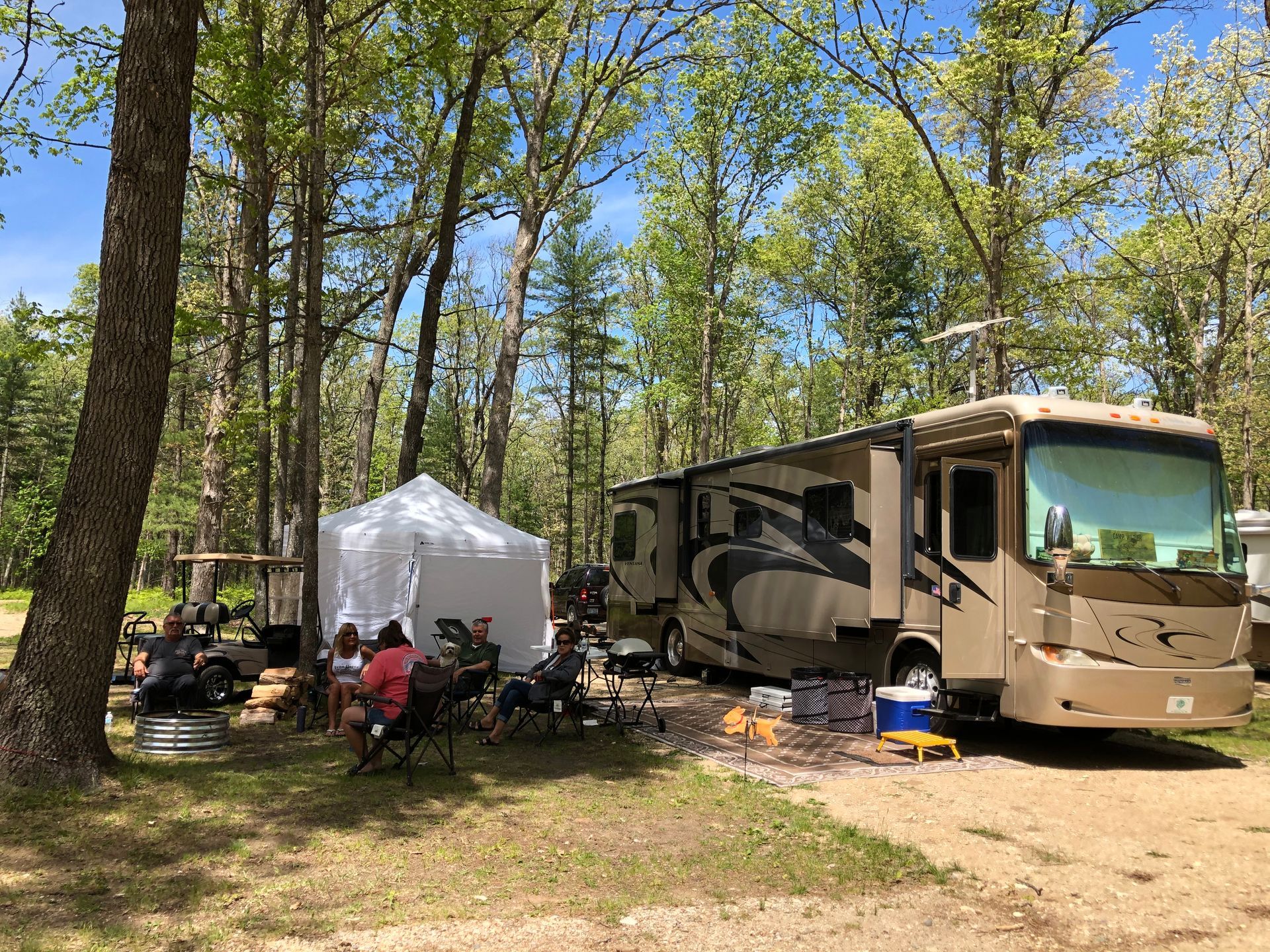 A rv is parked in a campground surrounded by trees.