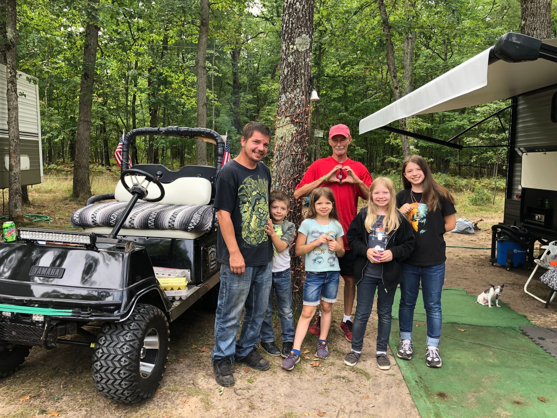 A group of people are standing in front of a golf cart.