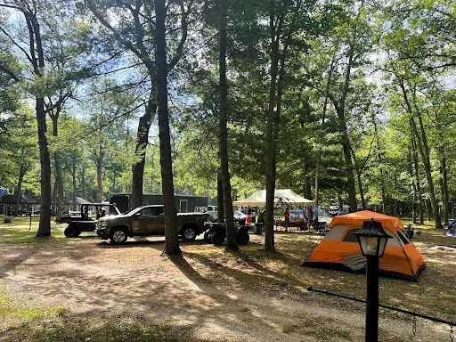 a truck is parked in a campground next to a tent .