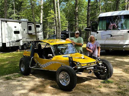 a man and a woman are standing next to a yellow buggy .