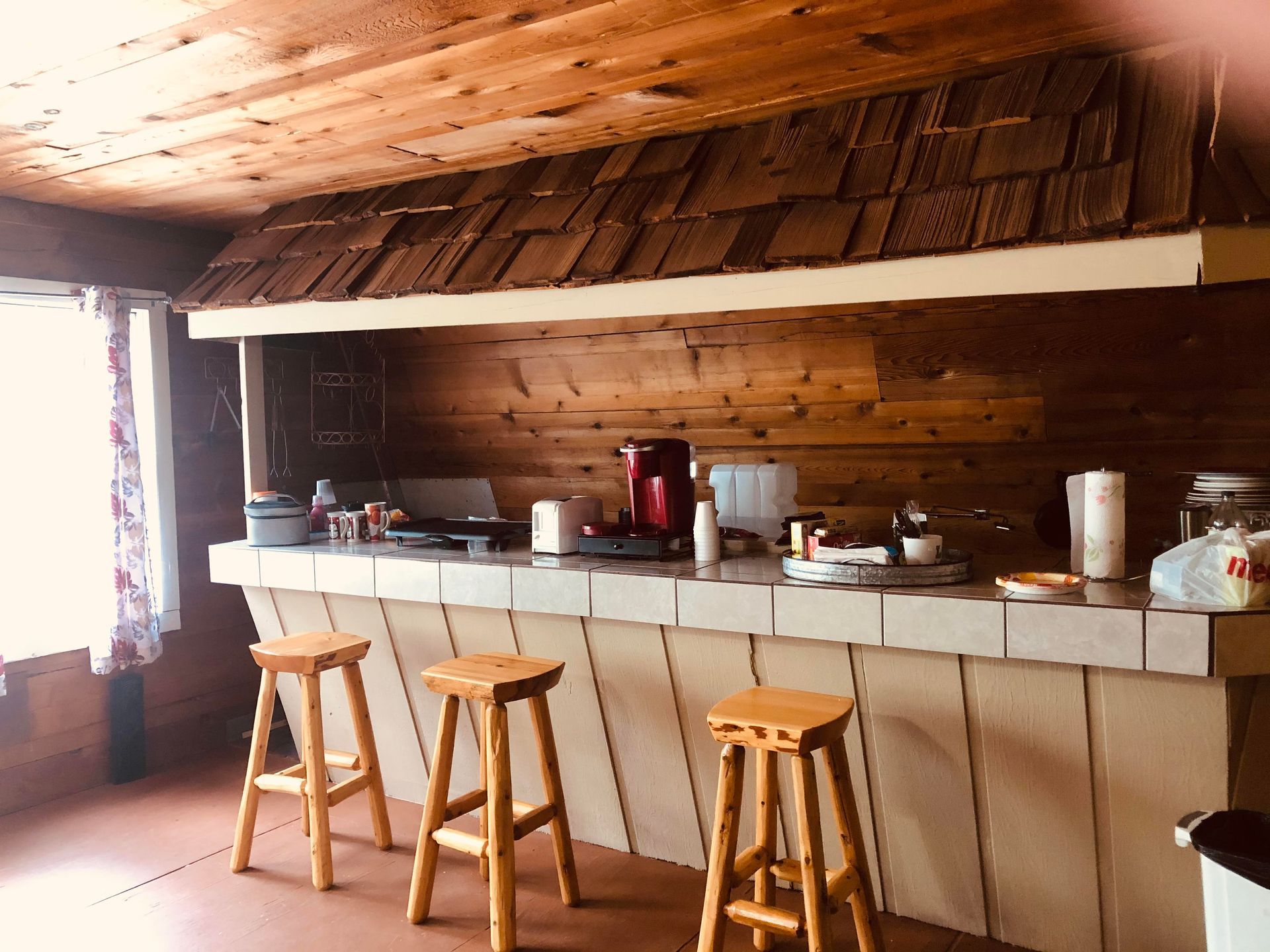A kitchen with a long counter and wooden stools.