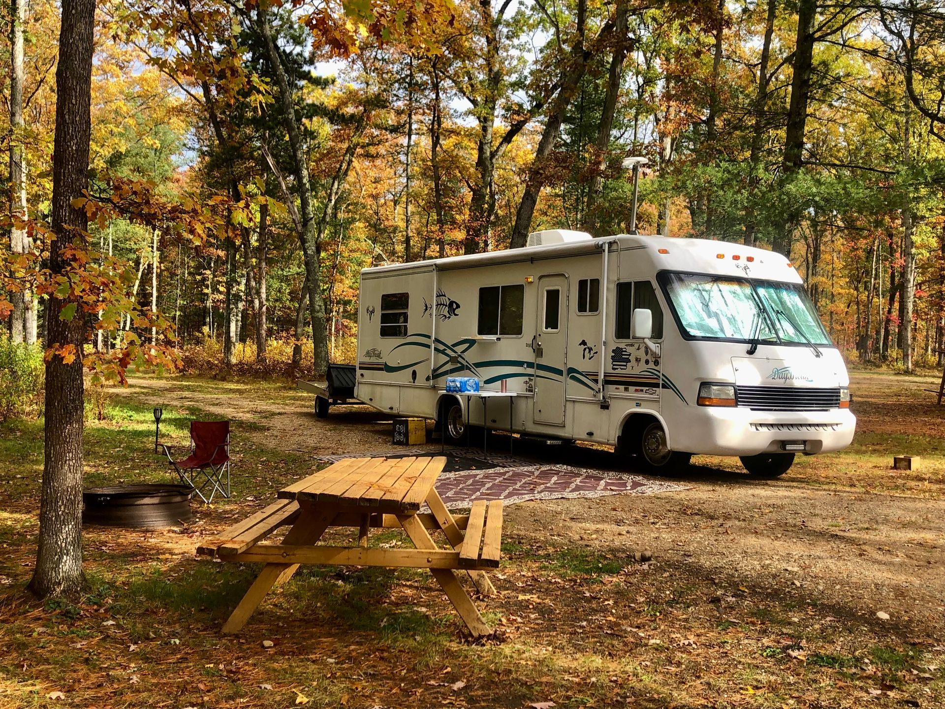 a rv is parked in a campground next to a picnic table .