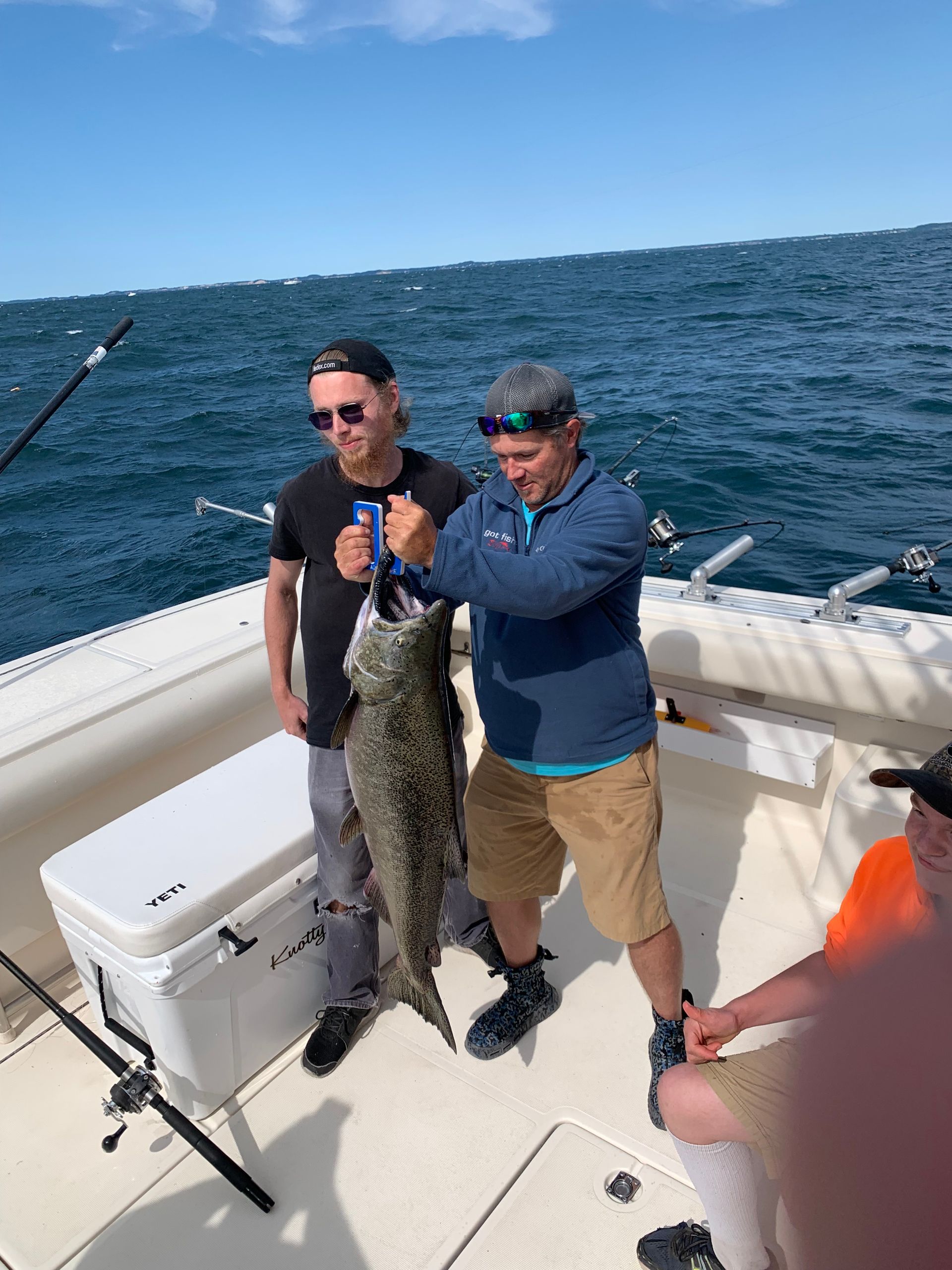 two men on a boat holding a large fish next to a yeti cooler