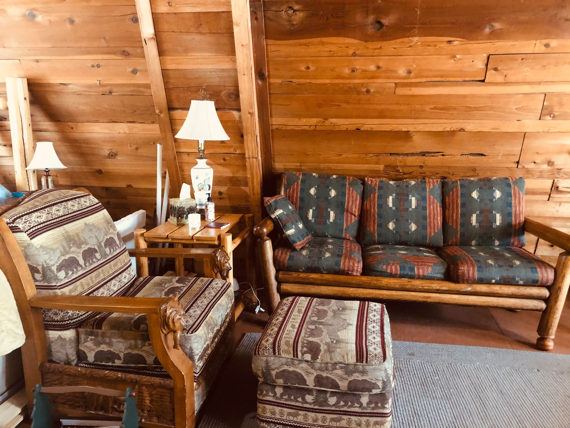A living room with a couch , chairs , ottoman and lamps.