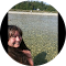 A woman is sitting in a circle in front of a body of water.
