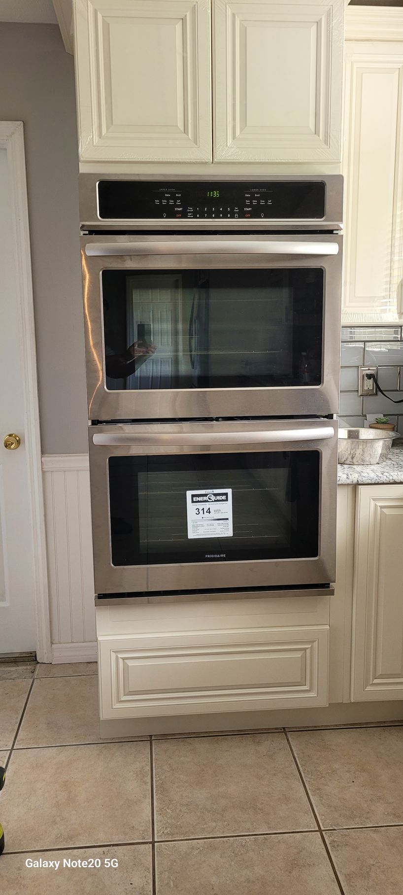 A double oven and microwave are stacked on top of each other in a kitchen.