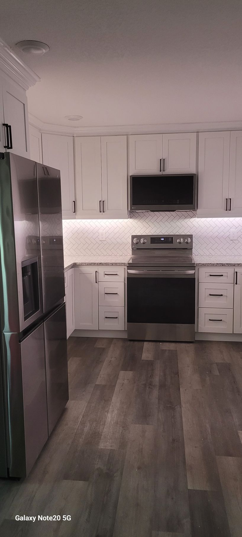 A kitchen with stainless steel appliances and white cabinets.