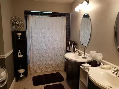 A bathroom with a sink , mirror and shower curtain.