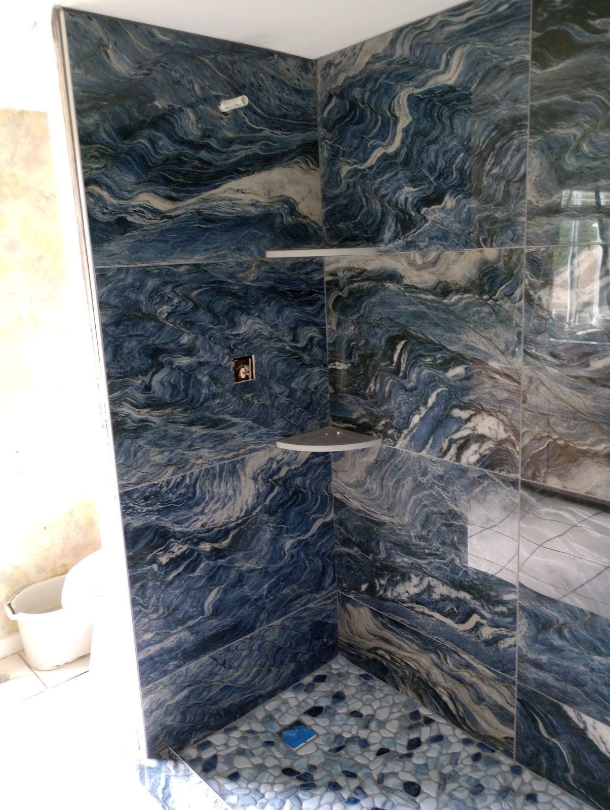 A bathroom with blue tiles and a walk in shower.