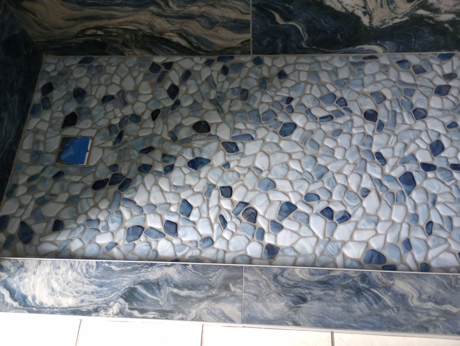 A shower stall with blue and white rocks on it