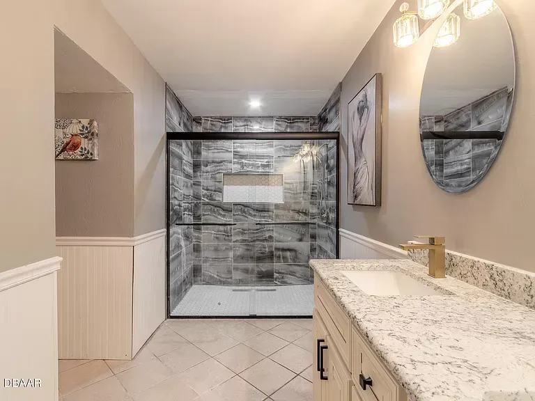 A bathroom with a sink , mirror and walk in shower.