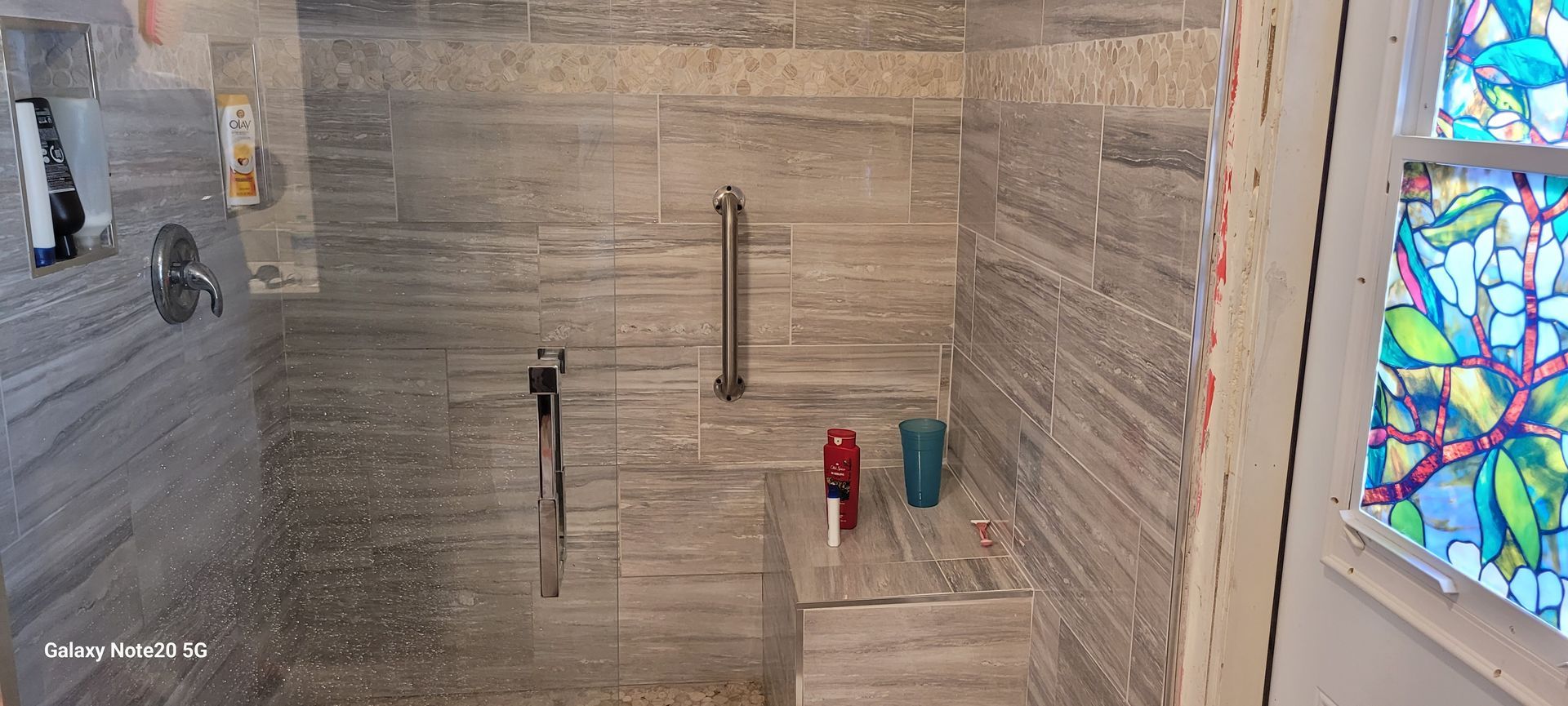 A bathroom with a walk in shower and a stained glass window.