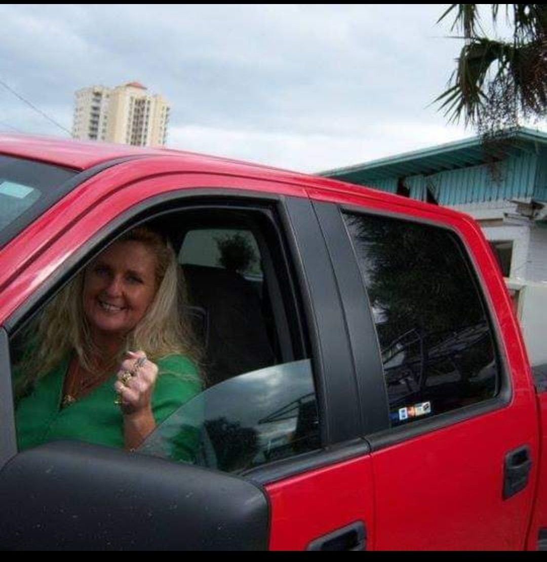 A woman in a green shirt is sitting in a red truck