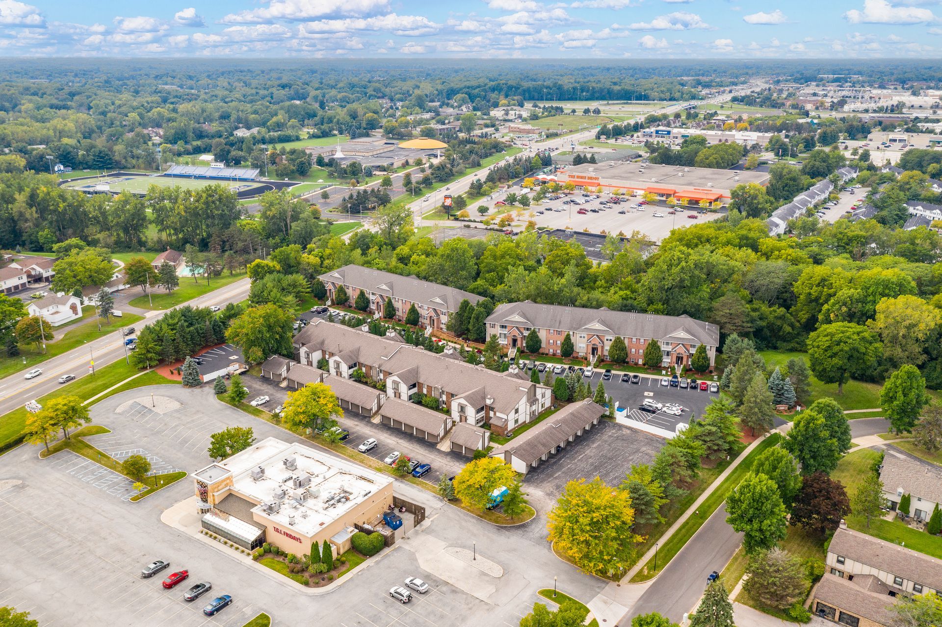 Aerial view of townhomes, businesses, and trees under a cloudy sky.