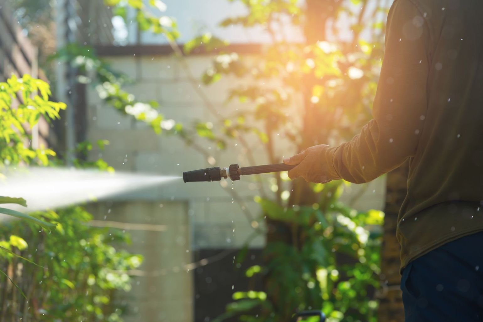 A man is using a high pressure washer to clean the outside of his house.