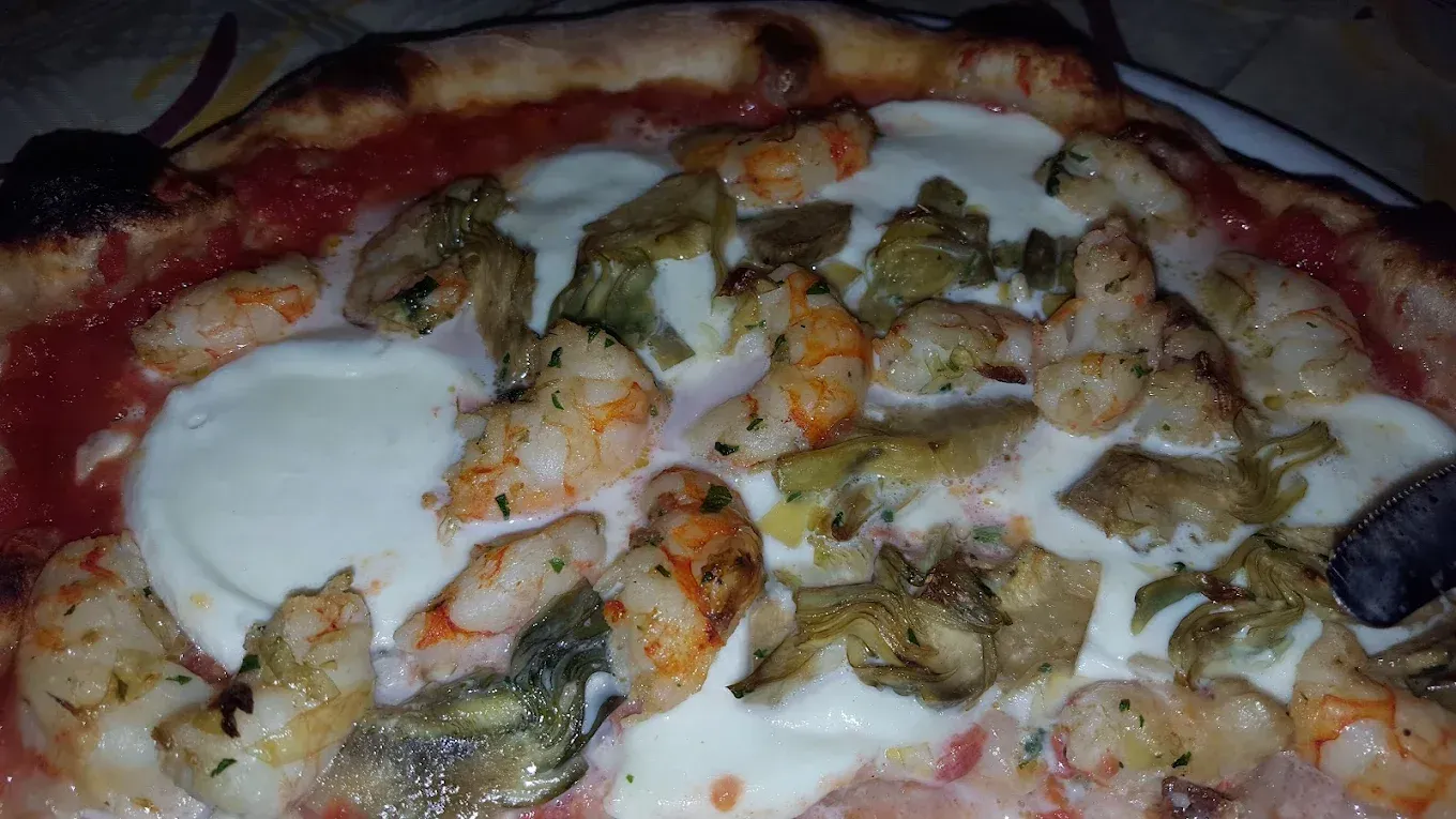Pizza con gamberi, carciofi e mozzarella su salsa di pomodoro.