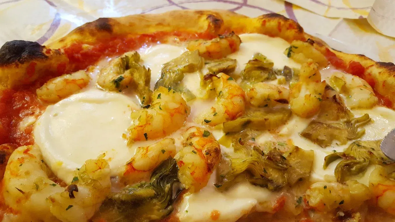 Pizza con gamberi, carciofi e mozzarella su una base di salsa di pomodoro.