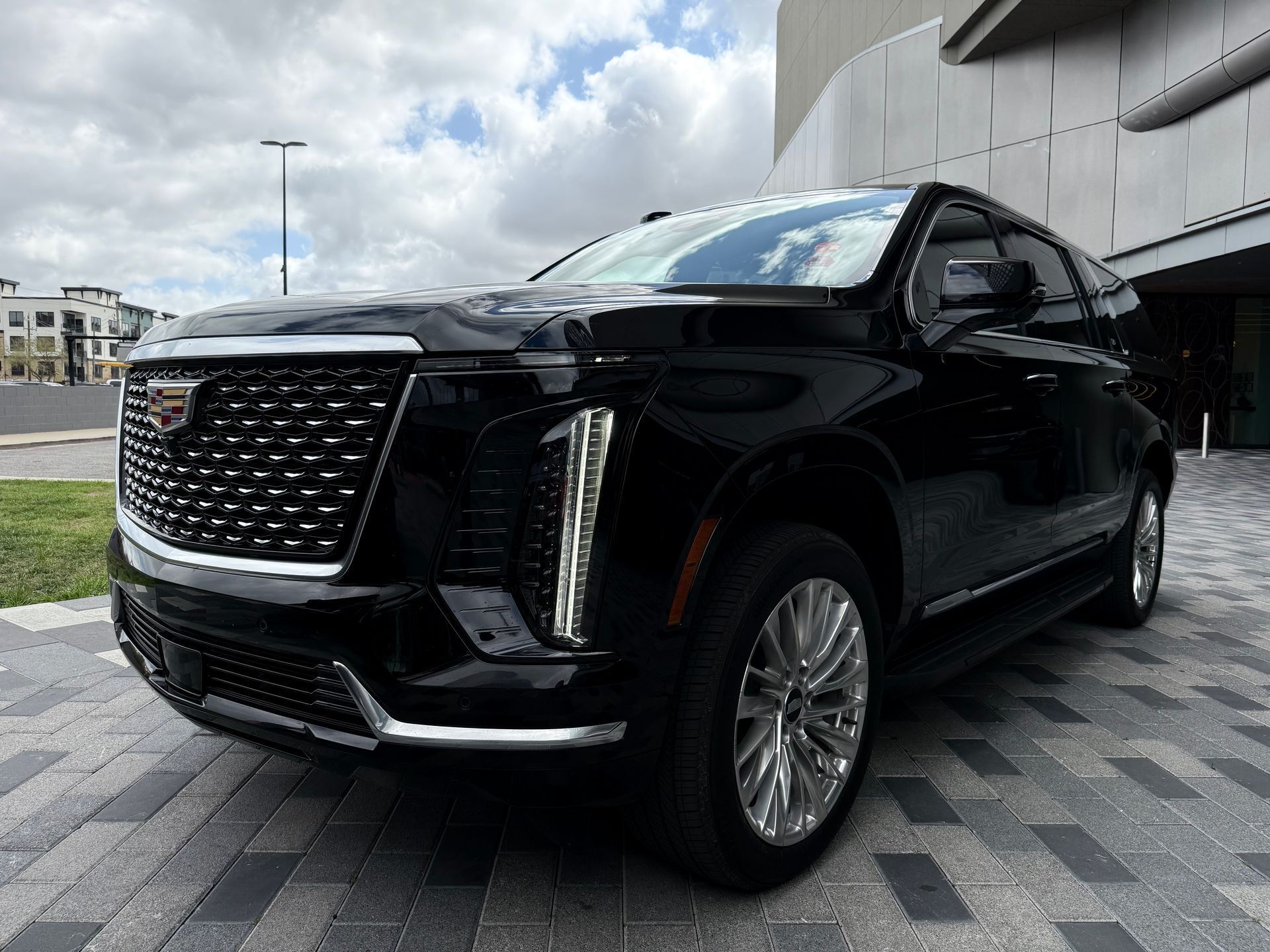 A black cadillac escalade is parked in front of a building.