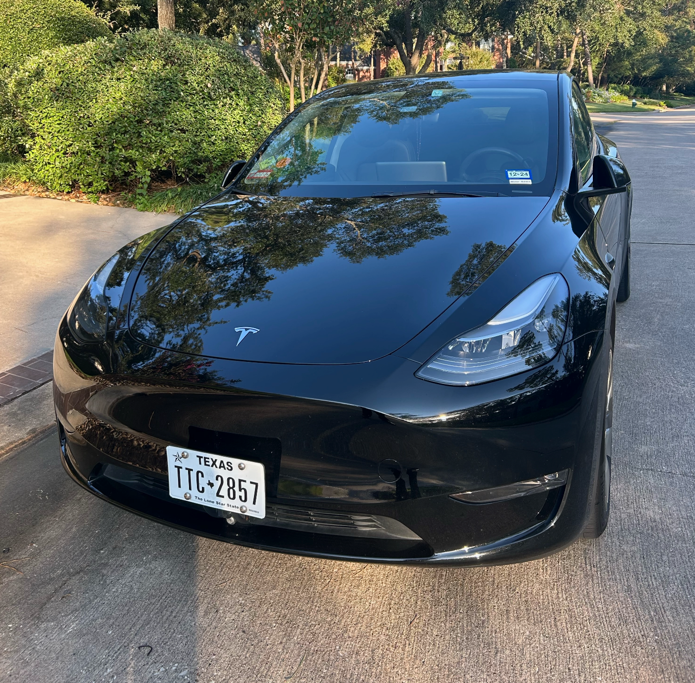 A black tesla model 3 is parked on the side of the road