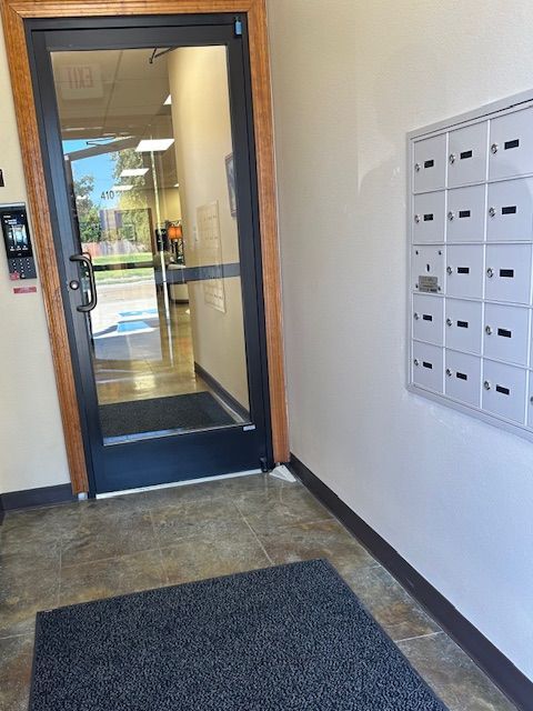 An entryway with a glass door, mailboxes, and a doormat.